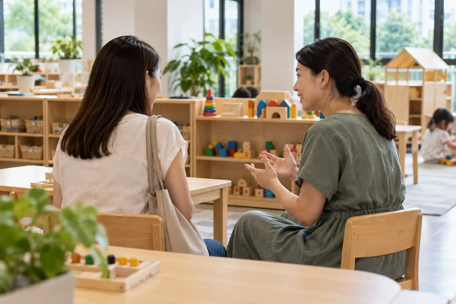 A parent speaking with a teacher during a preschool visit in a bright classroom